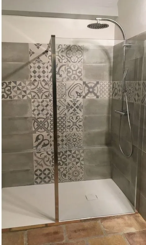 Après rénovation : douche à l'italienne, carreaux de ciment gris et paroi vitrée